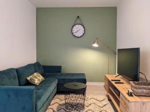 un soggiorno con divano blu e orologio sul muro di CasaCity Orléans Sud - 2 chambres - parking privé a Orléans