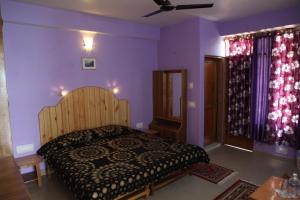 1 dormitorio con 1 cama y paredes moradas en Malis Apple Lodge, en Nagar