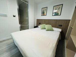 a bedroom with a large white bed with two green pillows at Habitacion Sevilla in Benidorm