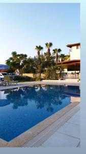 una piscina con agua azul y palmeras en MİNA GRAND HOTEL, en Kemer