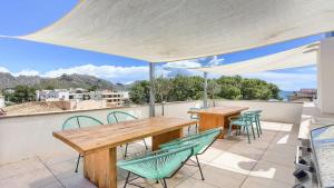 a patio with wooden tables and chairs on a roof at Apartment Alice in Port de Pollensa