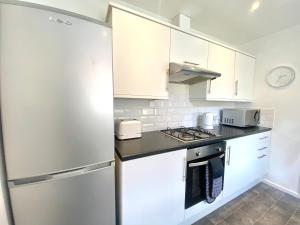 a kitchen with white cabinets and a refrigerator at Stylish 5 Beds House, TV, Garden in Rushden