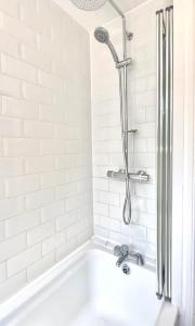 a white bath tub with a shower in a bathroom at Stylish 5 Beds House, TV, Garden in Rushden