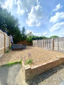 a backyard with a bench and a fence at Stylish 5 Beds House, TV, Garden in Rushden