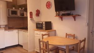 a small kitchen with a table and a microwave at Ustou Guzet neige, appartement de 32 M2 avec balcon dans les Pyrénées aux pieds des pistes in Ustou +25 photos
