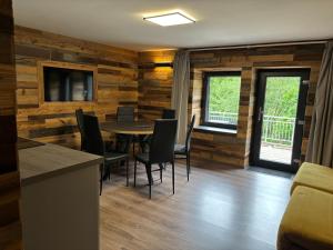 una sala da pranzo con pareti in legno, tavolo e sedie di La Ferme de Rochesson, Jacuzzis & Piscine commune a Rochesson