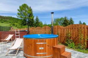 a hot tub in a backyard with a wooden fence at Apartamenty Szwarcowa in Tylicz