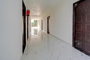 Hotel O Hira Royal Palace And Lawn في لاكناو: ممر فارغ بجدران بيضاء وباب بني