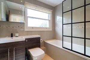 a bathroom with a toilet and a sink and a window at Lamington Apartments - Hammersmith in London