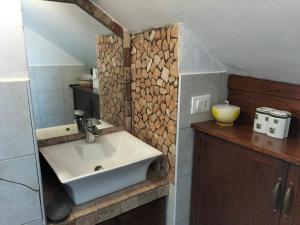 baño con lavabo y pared de troncos en Il Cantinoccio B&B en Cerasolo