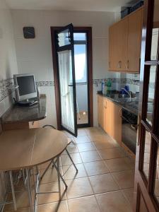 a kitchen with a table and a computer on a counter at Apartamento Portela in Bueu