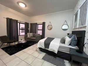 a bedroom with a bed and a couch and a chair at Crystal Lagoon Homes in Pretoria