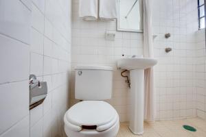 a white bathroom with a toilet and a sink at Hotel Huautla de Oaxaca in Oaxaca City