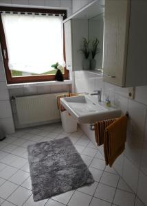 a white bathroom with a sink and a mirror at Am Lindenbaum, Ferienwohnung in Siebenbach am Nürburgring in Siebenbach