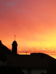 a sunset with a cross on top of a building at Am Lindenbaum, Ferienwohnung in Siebenbach am Nürburgring in Siebenbach