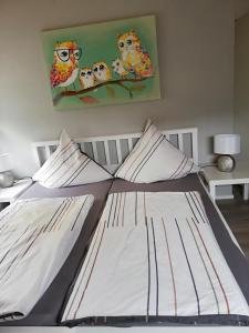 Bett in einem Schlafzimmer mit einem Eulengemälde in der Unterkunft Am Lindenbaum, Ferienwohnung in Siebenbach am Nürburgring in Siebenbach