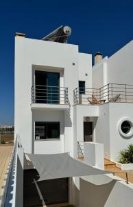 Cette maison blanche dispose d'un balcon et d'un ciel bleu. dans l'établissement Casa "Vento" Ferragudo mit privatem Pool, à Ferragudo