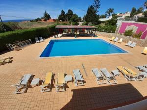 a swimming pool with a bunch of chairs and a group at Aurora Sol in Luz