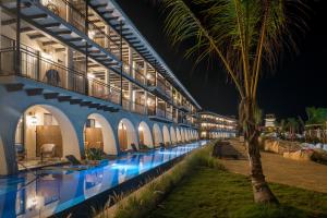 a swimming pool with a palm tree next to a building at Ocean el Faro Resort - All Inclusive in Punta Cana