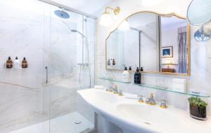 uma casa de banho branca com um lavatório e um chuveiro em Hotel Claridge Paris em Paris