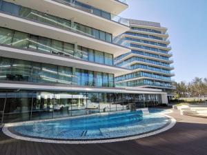 a large building with a swimming pool in front of it at Wave Międzyzdroje Luxury Apartment MORENORENT in Międzyzdroje