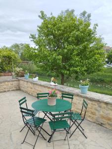 stół z 4 krzesłami oraz stół z kwiatami na patio w obiekcie Maison Chez Marinette w mieście Verdun-sur-le-Doubs