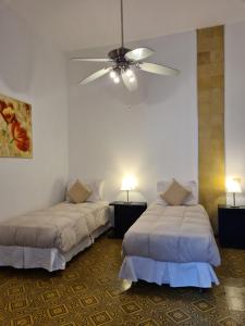 sypialnia z 2 łóżkami i wentylatorem sufitowym w obiekcie Posada El Capullo w mieście Colonia del Sacramento