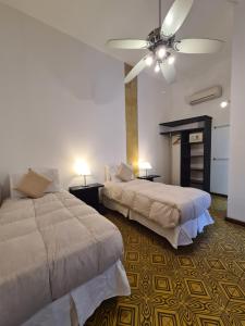 a bedroom with two beds and a ceiling fan at Posada El Capullo in Colonia del Sacramento