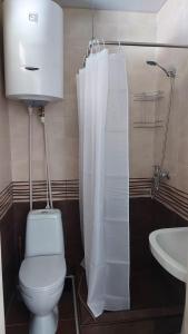 a bathroom with a toilet and a sink with a shower curtain at M7 House in Gorists'ikhe