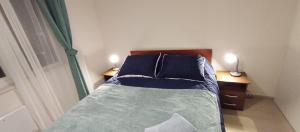 1 dormitorio con 1 cama con sábanas azules y 2 mesitas de noche en Departamento Avenida Austral, en Puerto Montt