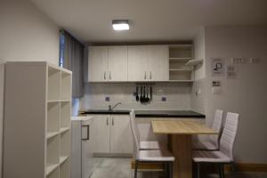 a kitchen with white cabinets and a wooden table and chairs at Hostel Pirano in Piran