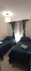 1 dormitorio con 2 camas con sábanas azules y ventana en Departamento Avenida Austral, en Puerto Montt
