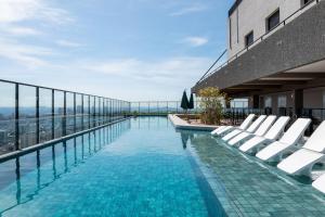 a swimming pool on the roof of a building with white chairs at Lindos apto com piscina no Setor Oeste IDV in Goiânia