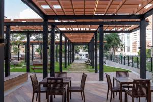 un patio con mesas y sillas y vistas a un parque en Lindos apto com piscina no Setor Oeste IDV en Goiânia