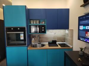 een keuken met blauwe kasten, een wastafel en een magnetron bij N Lux 95 Milmari in Kopaonik