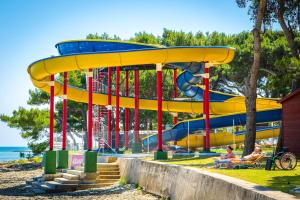 a playground with a yellow slide on the beach at Apartments Riva in Medulin