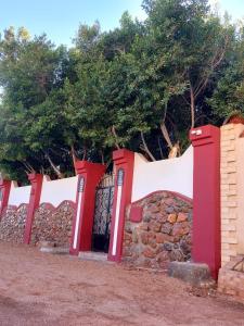 a fence with red and white gates and trees at Red oasis in Dahab
