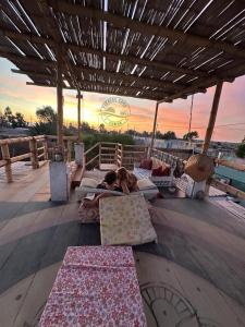 パラカスにあるDesert Lodge Paracas&Toursの夕日を望むパティオ(枕の上に寝そべる2名)