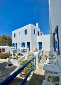 a white building with blue windows and white chairs at Marina In Town in Megali Ammos