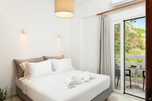 Habitación blanca con cama y balcón. en Thelèsi Apartments, en Stalós