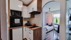 a small kitchen with white cabinets and a window at Krasnal in Ostróda