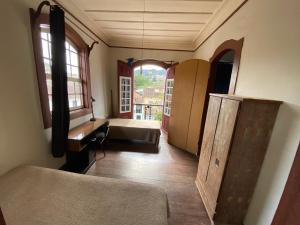 a room with a bed and a desk and window at República Birinaite in Ouro Preto