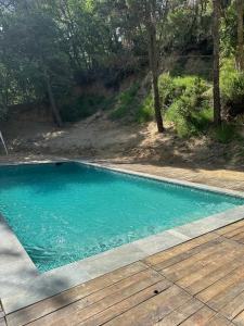 una piscina de agua azul y una terraza de madera en L'Amagatall de Cal Tonedor en Vallgorguina