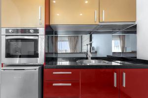 a kitchen with red cabinets and a sink at Ocean View Apartment in Albatros Golf del Sur in San Miguel de Abona +32 photos