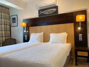 una habitación de hotel con una cama grande con sábanas blancas en Discovery Apartment Carnaxide, en Carnaxide