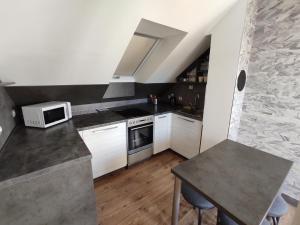 a small kitchen with white cabinets and a microwave at Apartmán Čeložnice in Čeložnice