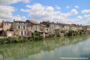a group of buildings on the side of a river at Logis Hôtel & Restaurant Le Saint Savinien in Saint-Savinien