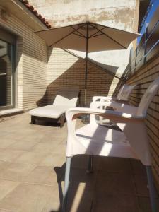 a white chair and an umbrella on a patio at Ático Entero con Habitación en Corella in Corella