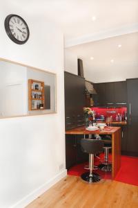une cuisine avec une table et une horloge murale dans l'établissement Chic & bright flat near Holyrood Park, à Édimbourg