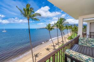 a balcony with a view of the beach and palm trees at Kihei Beach 606 - Direct Ocean Front, Central AC! in Kihei
